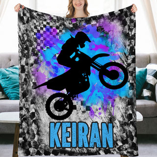 a woman holding up a blanket with a picture of a person on a dirt bike