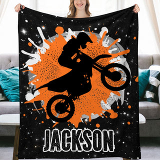 a woman holding up a black and orange blanket