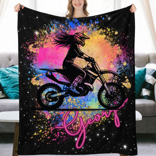 a woman holding up a blanket with a picture of a girl on a dirt bike