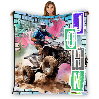 a woman holding up a blanket with a picture of a person riding a four wheeler