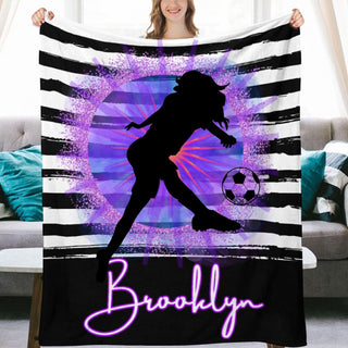 a woman holding up a purple and black blanket