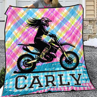 a woman holding a colorful blanket with a picture of a girl on a dirt bike