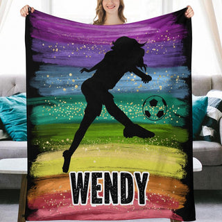 a woman holding up a colorful blanket with a picture of a girl kicking a soccer