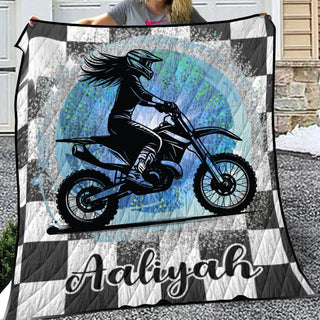 a woman holding up a blanket with a picture of a girl on a dirt bike