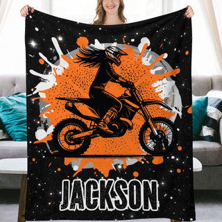 a woman holding up a black and orange blanket