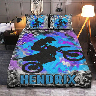 a bed with a blue and purple bed cover with a dirt bike on it