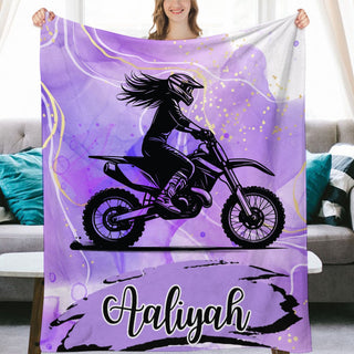 a woman holding a purple blanket with a picture of a girl on a dirt bike