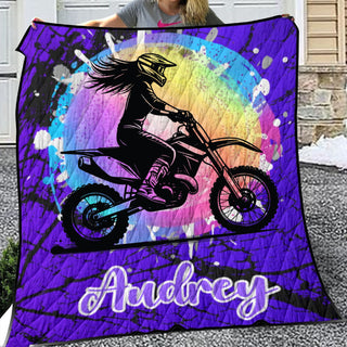 a woman holding up a blanket with a picture of a girl on a dirt bike