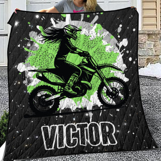 a woman holding up a quilt with a picture of a girl on a dirt bike