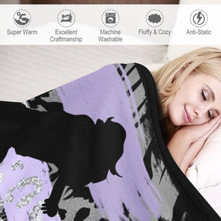 a woman laying in bed under a purple and black blanket