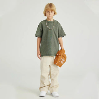 a young boy in a green shirt holding a brown bag