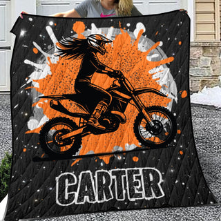 a woman holding up a blanket with a picture of a person on a dirt bike