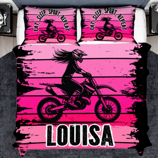 a bed with a pink and black bed cover with a girl on a dirt bike