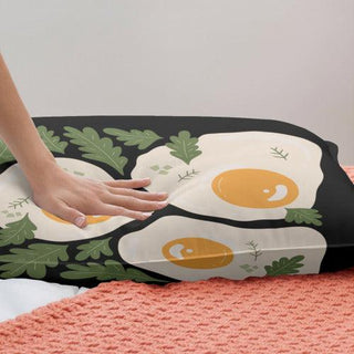 a person reaching for an egg pillow on a bed