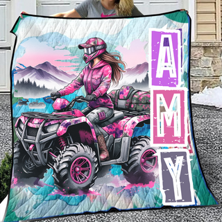 a woman holding up a quilt with a pink atv on it