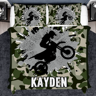 a bed with a camouflage print and a person on a dirt bike