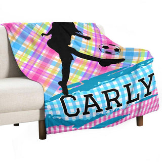 a couch with a blanket on it with a picture of a girl kicking a soccer