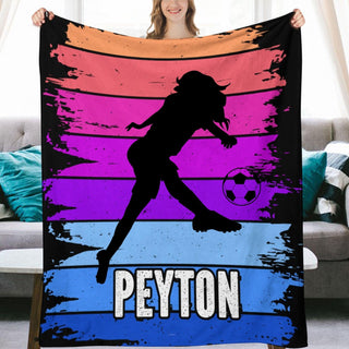 a woman holding up a blanket with a picture of a woman kicking a soccer ball