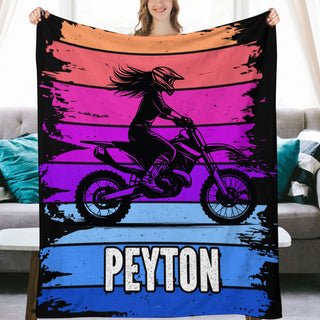 a woman holding up a blanket with a picture of a girl on a dirt bike