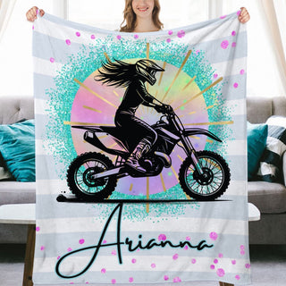 a woman holding up a blanket with a picture of a girl on a dirt bike