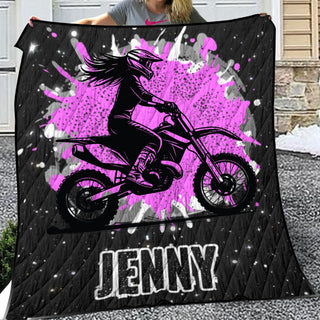 a woman holding up a blanket with a picture of a girl on a dirt bike