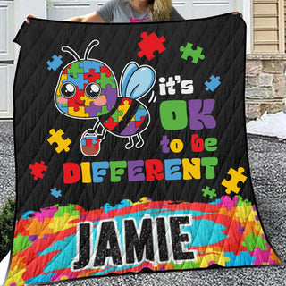 a woman holding up a black quilt with a picture of a bee on it