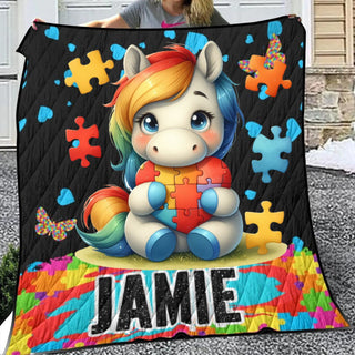 a girl holding up a quilt with a picture of a unicorn on it