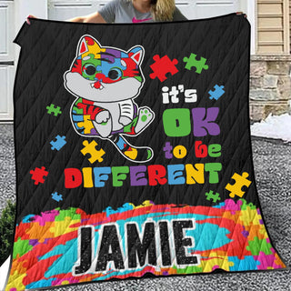 a woman holding up a quilt with a cat on it