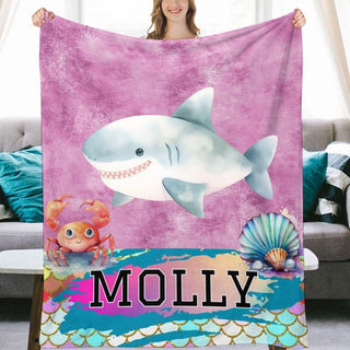 a woman holding a blanket with a picture of a shark on it