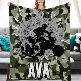 a woman holding up a camo blanket with a monster truck on it