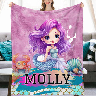 a girl holding a blanket with a mermaid on it