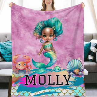 a woman holding a blanket with a picture of a mermaid on it