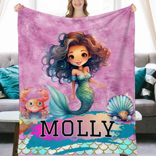 a woman holding a blanket with a picture of a mermaid on it