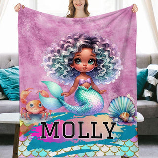 a woman holding a blanket with a picture of a mermaid on it