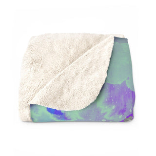 a white blanket with a blue and green design on it