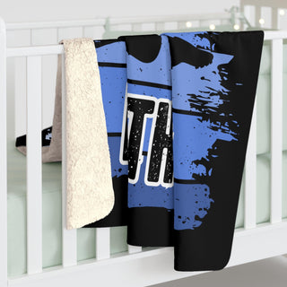 a baby crib with a blue and black blanket hanging from it's side