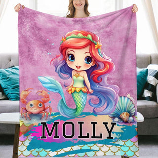 a woman holding a blanket with a picture of a mermaid on it