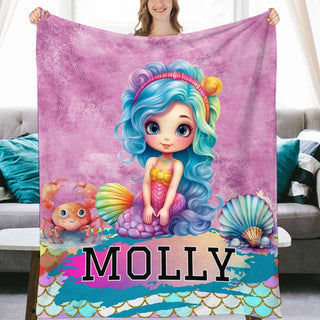 a woman holding a blanket with a picture of a mermaid on it