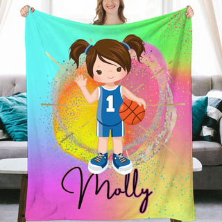 a girl holding up a colorful blanket with a basketball on it