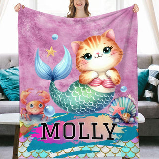 a cat sitting on top of a mermaid blanket