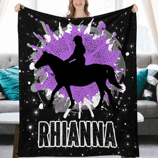 a woman holding a blanket with a picture of a woman riding a horse